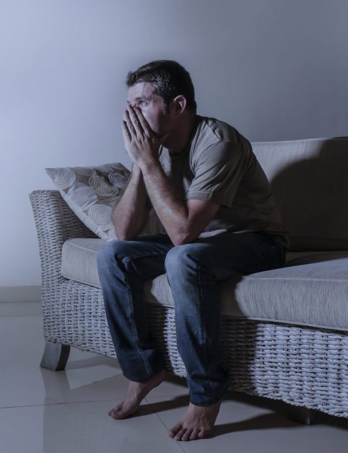 lifestyle dramatic light portrait of young sad and depressed man sitting at shady home couch in pain and depression feeling stressed and desperate lifestyle dramatic light portrait of young sad and depressed man sitting at shady home couch in pain and depression feeling stressed and desperate crying alone suffering anxiety crisis
