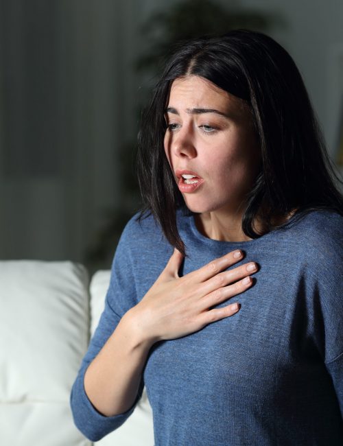 Woman suffering an anxiety attack alone in the night Woman suffering an anxiety attack alone in the night on a couch at home